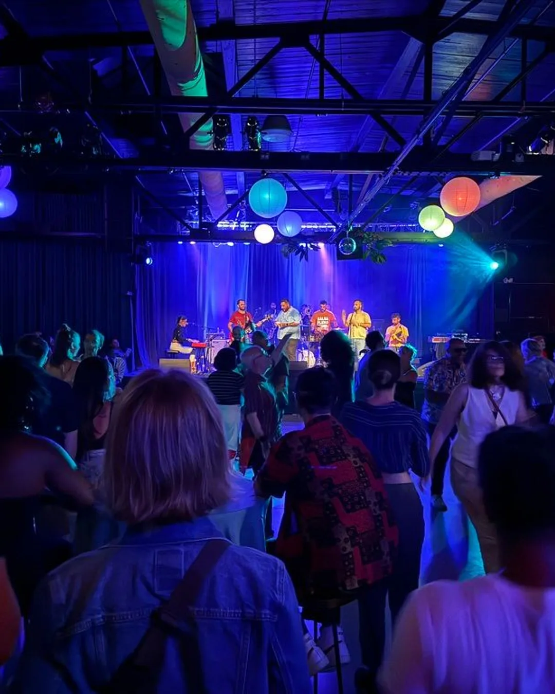 A crowd on the Soundstage floor facing a band under blue light and coloured paper lanterns