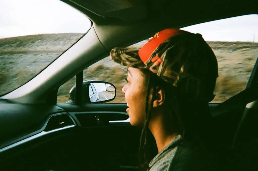 Person wearing cap driving a car on road